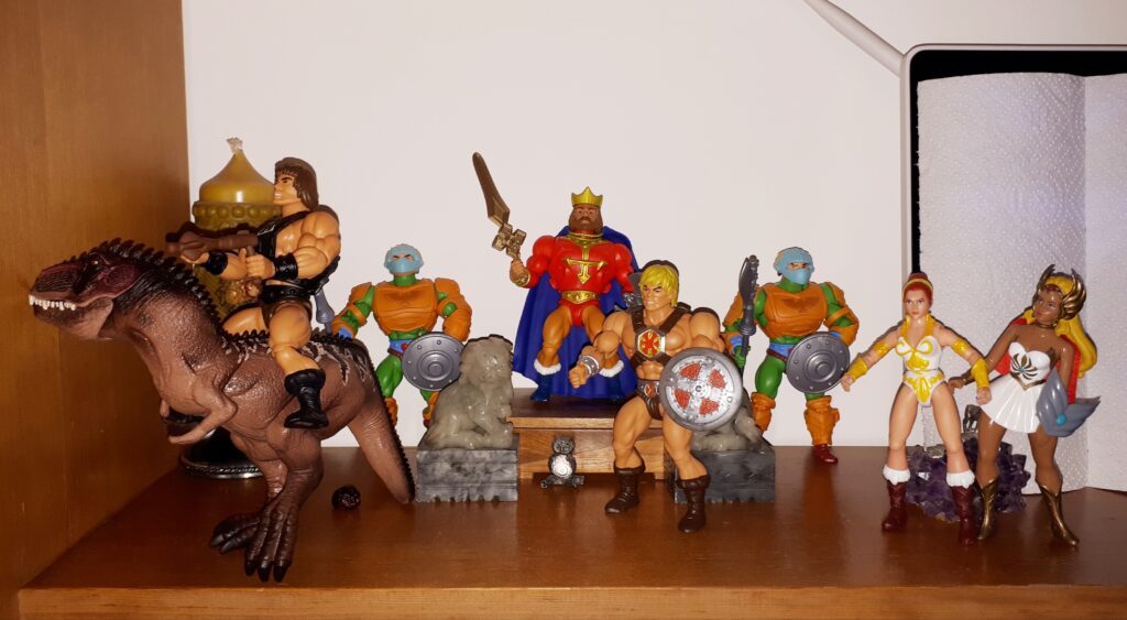 Wun-Dar rides off on Giga, while King Randor, He-Man, She-Ra, Teela and two guards look on.
