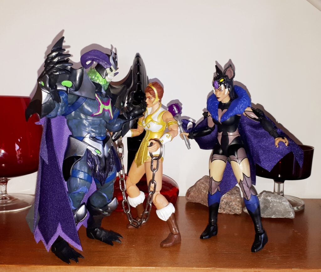 Skelegod harasses the captured Teela, while Evil-Lyn looks on.