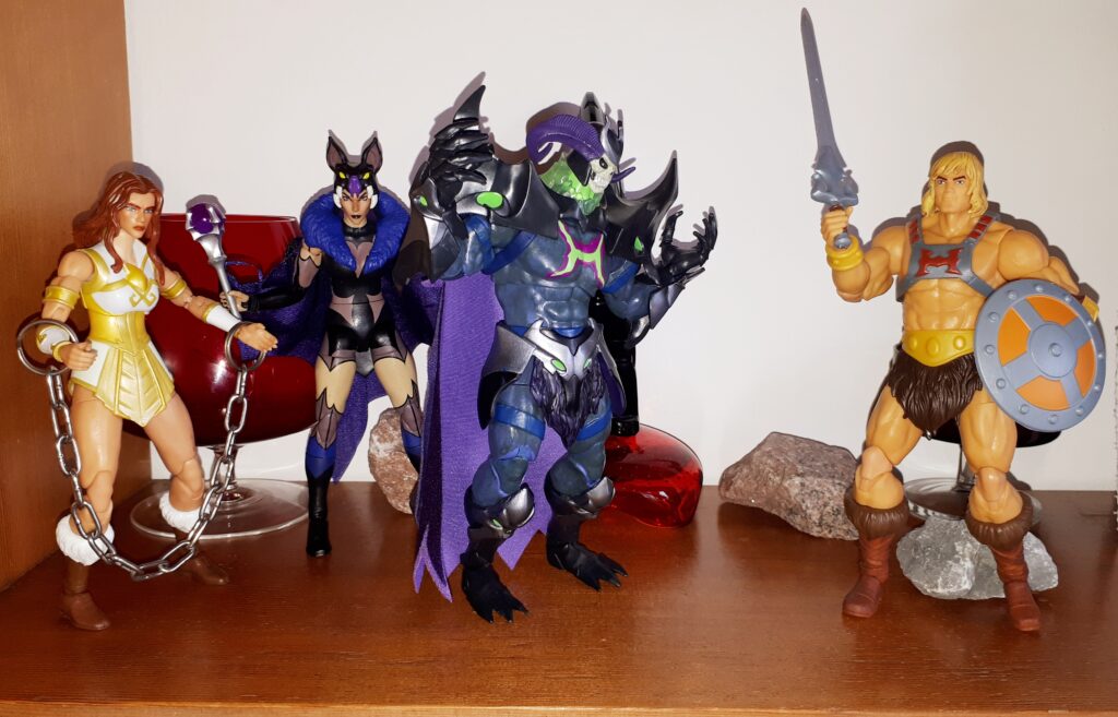 He-Man confronts Skelegod, while Evil-Lyn and the chained up Teela look on.
