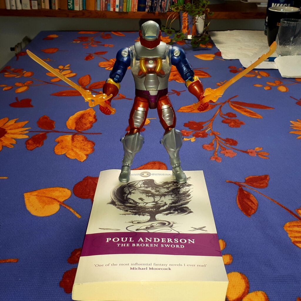 Roboto stands astride a copy of "The Broken Sword" by Poul Anderson, holding the two halves of the Power Sword