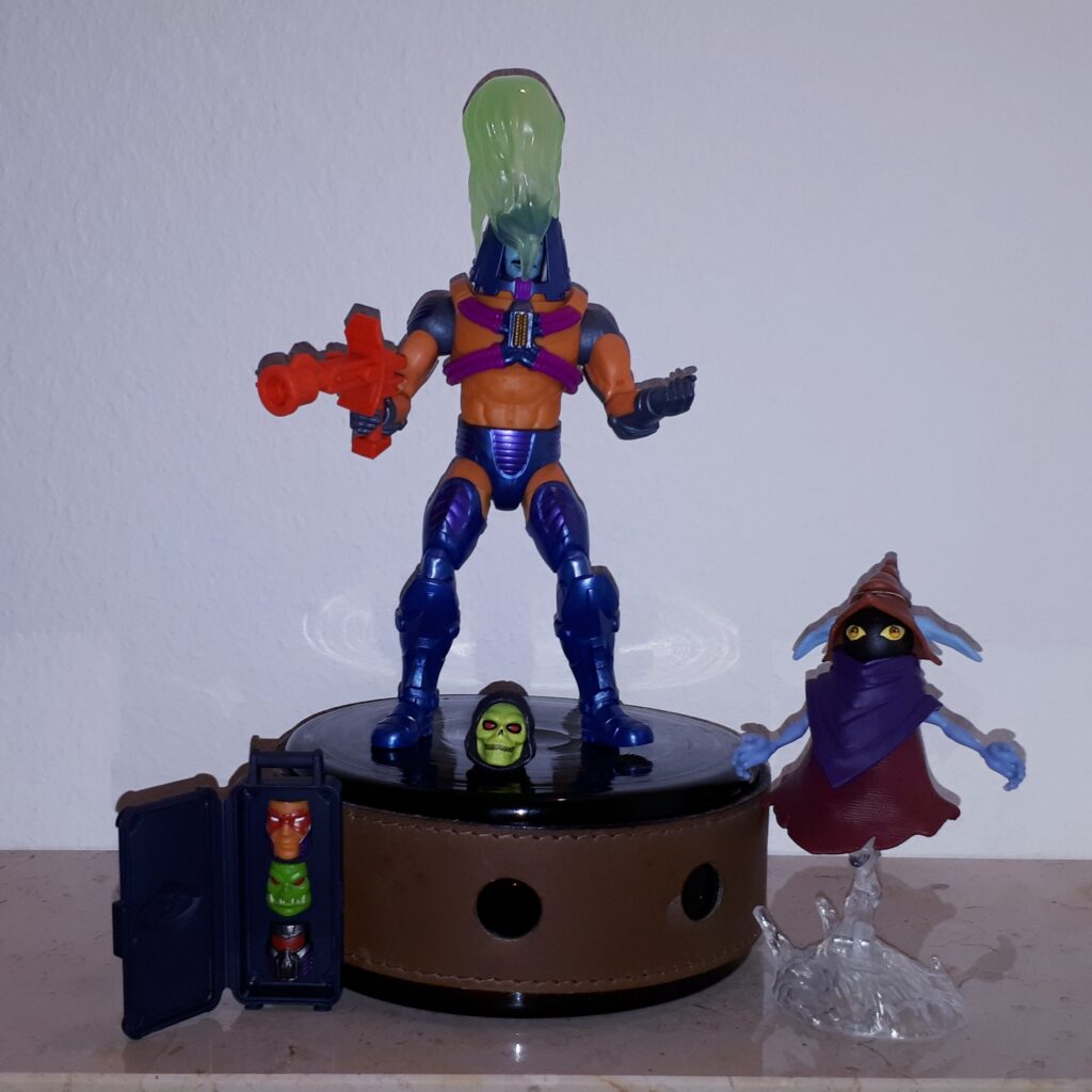 Man-e-Faces wears the Keldor face covered in acid, while Orko looks on.