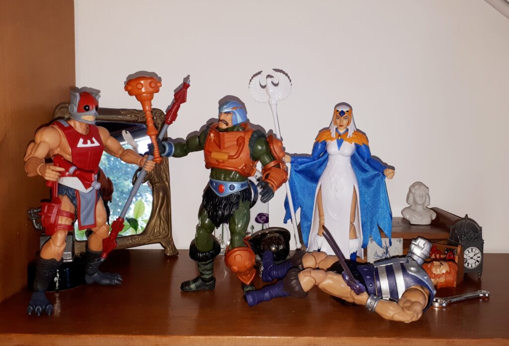 Duncan attacks Zodac with his mace, while Malcolm is down and the Sorceress looks on.